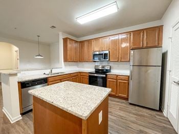 An empty kitchen with wooden cabinets and stainless steel appliances